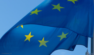 Eiropas Savienības karogs plīvo vējā, fonā zilas debesis